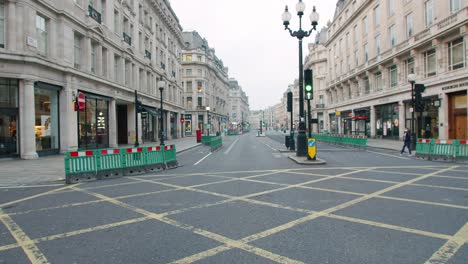 Lockdown-in-London,-lone-walker-in-completely-empty-Regent-Street-during-the-Coronavirus-pandemic-2020,-on-an-overcast-day