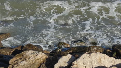 Waves-crashing-at-rocks-on-riverside-beach---Close-up