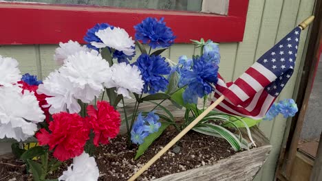 Langsame-Pfanne,-Rote-Weiße-Und-Blaue-Nelken-Und-Eine-Kleine-Amerikanische-Flagge,-Rustikaler-Blumenkasten
