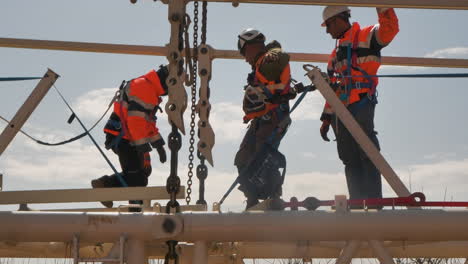 Three-workers-shown-in-slow-motion-on-an-elevated-building-structure-on-a-construction-site-in-Golan-Heights,-Israel