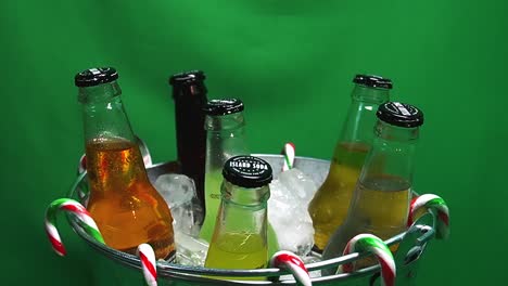 3-3-LOOP-Green-Screen-rotating-metalic-party-bucket-of-carbonated-Island-Soda-drinks-in-ice-with-hanging-candy-canes-and-water-droplets-on-glass-bottles-of-mango-ginger-pine-apple-lime-cola-cream