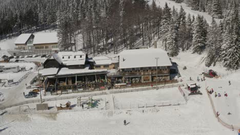 Kope-Ribnica-resort-and-RV-Park-at-the-Pohorje-mountains-during-the-winter,-Aerial-pan-left-reveal-shot