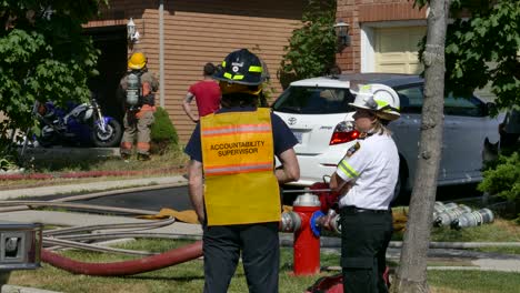 Firefighters-talking-together-at-scene-of-fire-in-suburban-area-in-Mississauga,-Canada