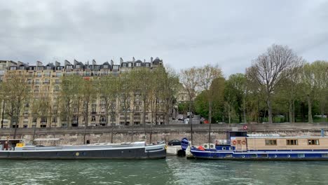 Una-Vista-Lateral-De-Los-Edificios-Al-Lado-Del-Río-Sena-Mientras-Toma-Un-Paseo-En-Barco-Turístico-En-París,-Francia