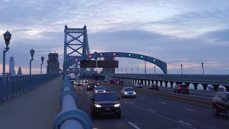 Panorama-Der-Skyline-Von-Philadelphia,-Ben-Franklin-Bridge-Bei-Sonnenuntergang,-Während-Autos-Und-Lastwagen-Vorbeifahren---Statische-Aufnahme