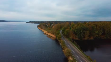Aerial-View-of-Colorful-Forest-and-Trafic-Road-at-River-Daugava-in-Latvia