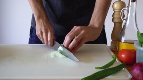 Man's-Hands-Slicing-White-Onion-In-The-Kitchen,-close-up