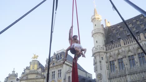 Young-couple-of-street-performers-giving-entertaining-gymnastics-show-at-the-Grand-Place-of-Brussels,-Belgium-on-a-warm-summer-evening-during-sunset