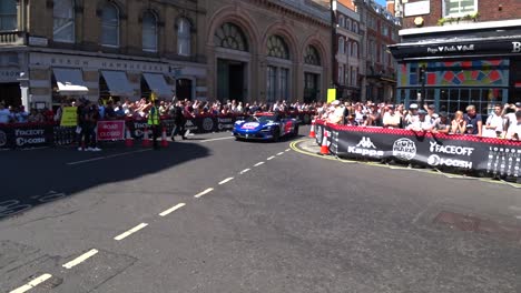 Luxury-racing-cars-driving-on-the-roads-in-London-with-many-celebrating-people-visiting-the-famous-Gumball-3000-Show-in-the-UK