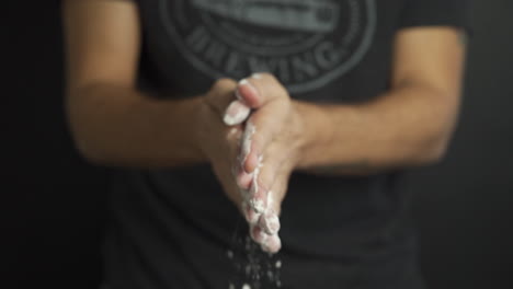 Slow-motion-of-a-Baker-with-flour-in-his-hands-while-clapping-and-flour-particles-are-released-in-the-air,-cinematic-shot