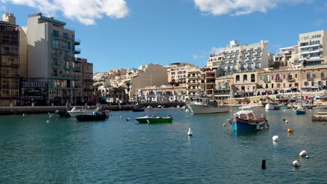 Fishing-Boats-in-Spinola-Bay,-Malta-in-a-Summer-Day-Floating-in-calm-sea-water