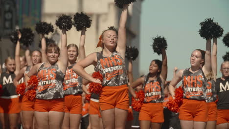Young-blonde-football-cheerleader-leading-squad-during-parade,-Slow-Motion