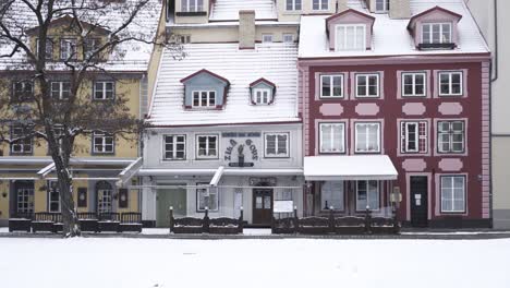 Caminando-Por-Una-Calle-Cubierta-De-Nieve-En-Riga-Letonia-Con-Vistas-A-Las-Coloridas-Fachadas-De-Casas-Y-Restaurantes-En-Invierno,-Pov,-Tiro-De-Seguimiento
