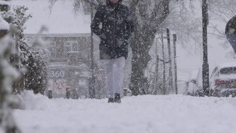 Einsame-Frau,-Die-Bei-Schneefall-Auf-Schneebedecktem-Bürgersteig-Spazieren-Geht