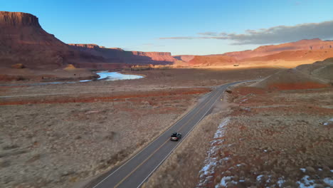 Un-Dron-Sigue-A-Un-Automóvil-Por-Una-Carretera-Vacía-A-Lo-Largo-Del-Río-Colorado-Cerca-De-Moab,-Utah