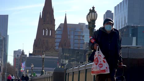 A-man-wearing-a-mask-walks-by-Melbourne's-famous-landmarks---Victoria,-Australia