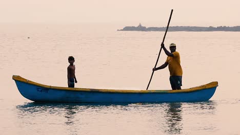 Fisherman-rowing-a-small-wooden-boat-and-teaching-young-boy-a-traditional-methods-of-fishing-and-rowing-boat-in-shallow-water-video-background-in-full-hd-in-mov