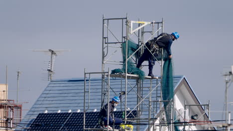 Japanische-Bauarbeiter,-Die-Während-Einer-Pandemie-In-Tokio,-Japan,-Arbeiten-Und-Sicherheitsnetze-Auf-Gerüste-Setzen