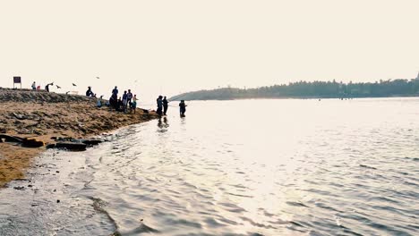 Eine-Gruppe-Von-Menschen,-Die-In-Der-Nähe-Eines-Strandes-In-Einer-Kleinen-Bucht-Mit-Angelruten-Während-Des-Hintergrundvideos-Der-Sonnenuntergangszeit-In-4k-Fischen