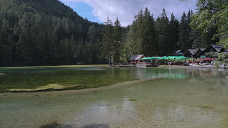 People-enjoy-a-sunny-day-on-the-shore-of-Lake-Plansar-in-Zgornje-Jezersko,-Slovenia