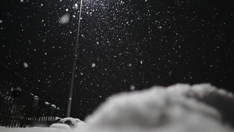 Low-angle-shot-of-heavy-snowfall-at-night-with-lighting-lantern-outdoors-in-nature