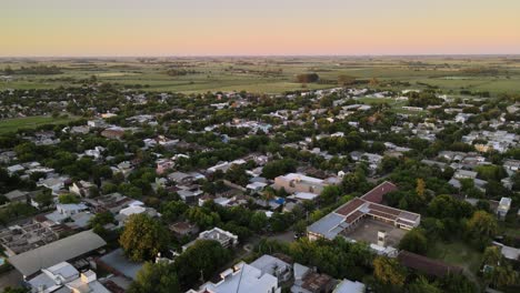 Dolly-in-flying-over-dreamy-Santa-Elisa-green-countryside-town-with-farmlands-in-background-at-sunset,-Entre-Rios,-Argentina