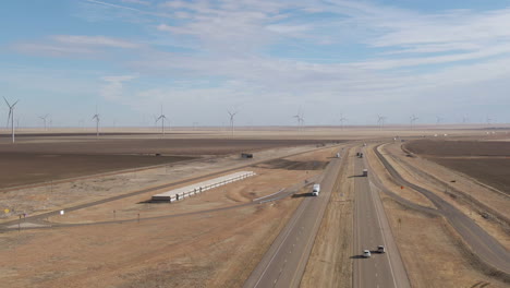 Aerial-tracking-shot-over-Interstate-40-in-north-Texas,-with-massive-wind-farm-in-the-background