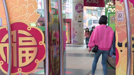Shoppers-walk-through-a-door-with-Chinese-Lunar-New-Year-decorative-theme-doors,-during-the-preparations-for-the-upcoming-Chinese-lunar-new-year-Ox-holidays