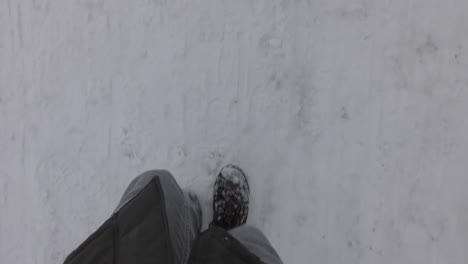 Die-Beine-Der-Person-Laufen-An-Kalten-Wintertagen-Auf-Einer-Verschneiten-Straße