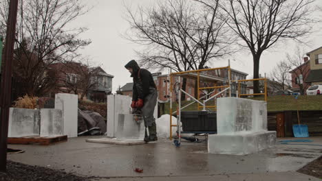 Wide-shot-of-sculptor-moving-ice-block-with-ice-tongs,-Slow-Motion
