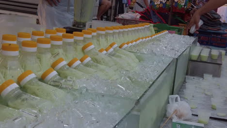 Close-up-shots-of-plastic-bottles-with-yellow-cap-on-top,-buried-into-crushed-ice-with-people-in-the-background