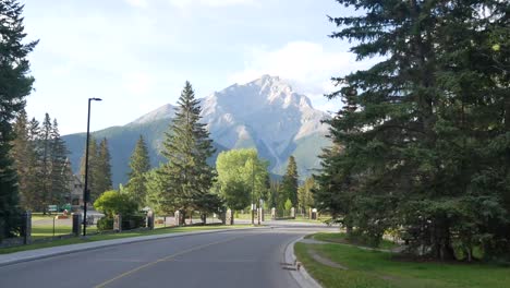 Landschaftsansicht-Aus-Dem-Fahrenden-Auto-Der-Stadt-Banff-Mit-Hoher-Bergkette-Der-Hauptstraße-In-Banff,-Alberta,-Kanada