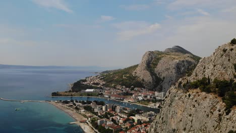 Hazy-sunny-summer-day-aerial-panoramic-footage-over-Omis-town,-river-Cetina-and-cliffs