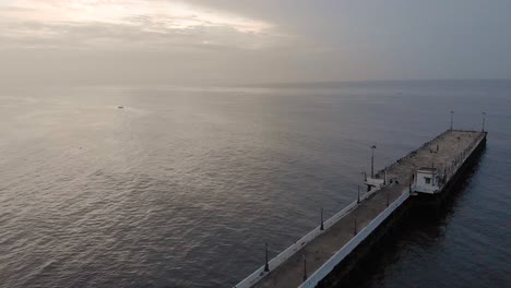 4k-Aerial-Dolly-shot-of-a-Shipping-Port-Pier-on-a-Sunrise-with-monsoon-clouds-covered-near-Rock-Beach-shot-with-a-drone,-Pondicherry,-India