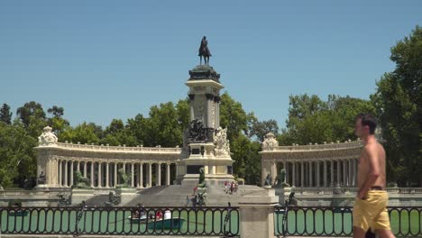 Locked-off-frontal-view-over-pond-in-Retiro-Park-in-Madrid-with-people-walking-through-frame