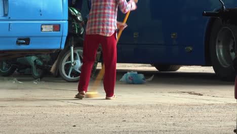 Close-Shot-of-the-Lady-Brooming-the-Dust-at-the-Bus-Station
