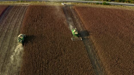 Aerial-reveal-of-John-Deere-combine-harvesting-agricultural-machinery-in-sunflower-fields-in-Bulgaria