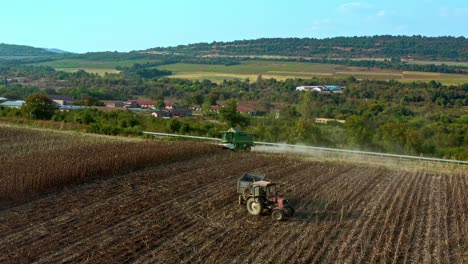Establishing-aerial-drone-shot-of-John-Deere-combine-tractor-harvesting-sunflower-seeds-during-summer-evening-in-Bulgarian-rural-countryside