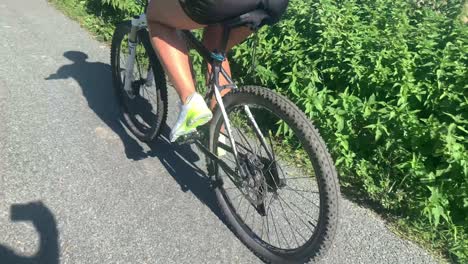 Rear-view-of-beautiful-caucasian-female-legs-riding-a-mtb-mountain-bike-down-the-road
