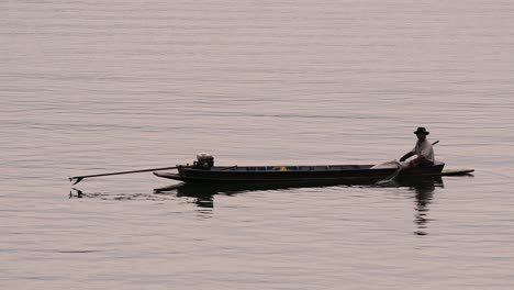 Fisherman-silhouetting-as-he-is-casting-and-drawing-his-net-in-the-River-before-dark,-in-slow-motion