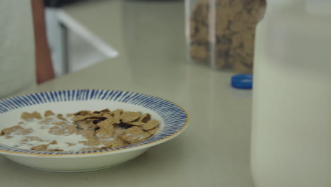 Close-up-tracking-shot-of-man-pouring-milk-onto-his-cereal