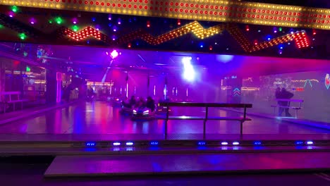 Cheerful-People-having-fun-in-illuminated-bumper-cars-at-carnival-event,static