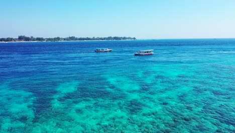 Bali,-Indonesia,-Dos-Barcos-De-Pesca-Navegando-En-El-Mar-Cristalino,-Pequeña-Isla-En-El-Fondo,-Antena