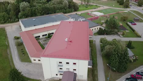 Aerial-flyover-of-local-school-building,-revealing-playing-ground-next-to-it