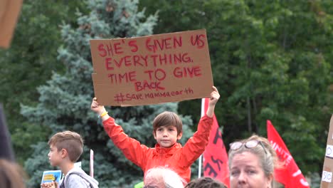 Little-boy-holding-up-poster-during-global-climate-change-march