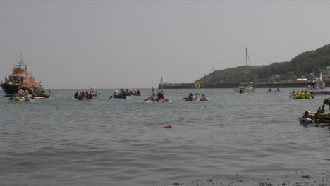 Local-business-teams-halfway-at-the-Newlyn-raft-race-charity-fun-outdoors-event,-Cornwall