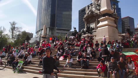 tilt-down,-people-taking-a-rest-on-the-feet-of-important-monument-in-Mexico