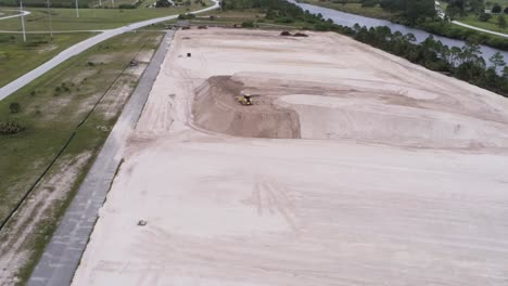Overheard-view-of-yellow-tractor-at-a-construction-site,-aerial-drone-shot
