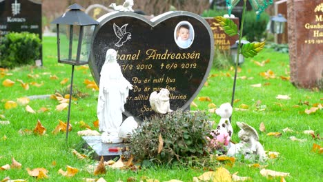 La-Lápida-De-Un-Niño-Con-Las-Estatuas-Católicas-En-El-Cementerio-De-Kviberg-En-Gotemburgo,-Suecia---Toma-Panorámica