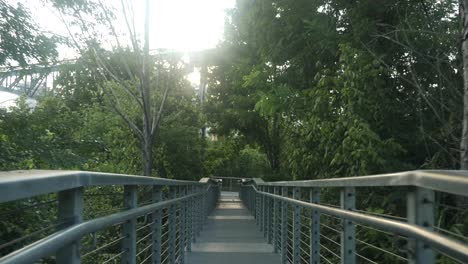 POV-walking-down-a-bridge-on-a-path-in-a-park